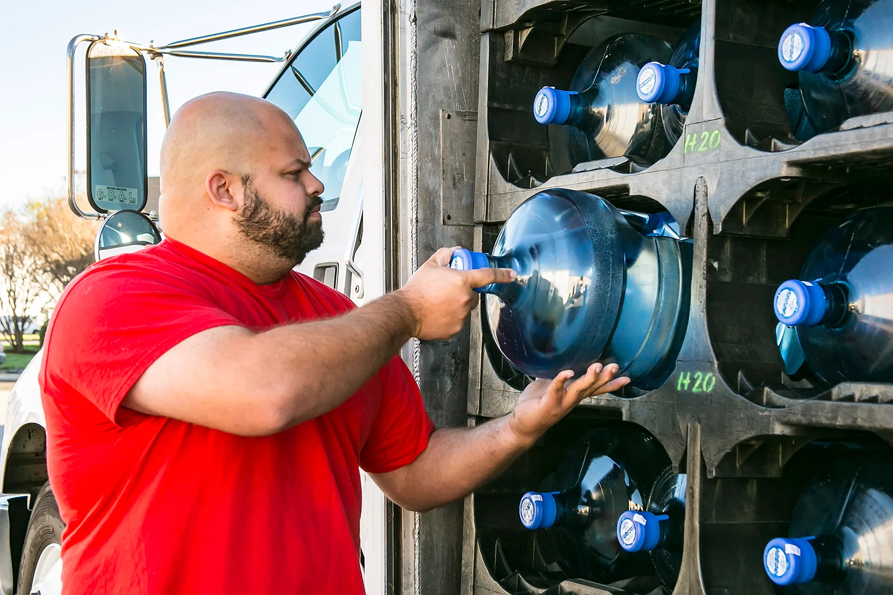 H2O to Go team member loading purified water jugs onto a delivery truck